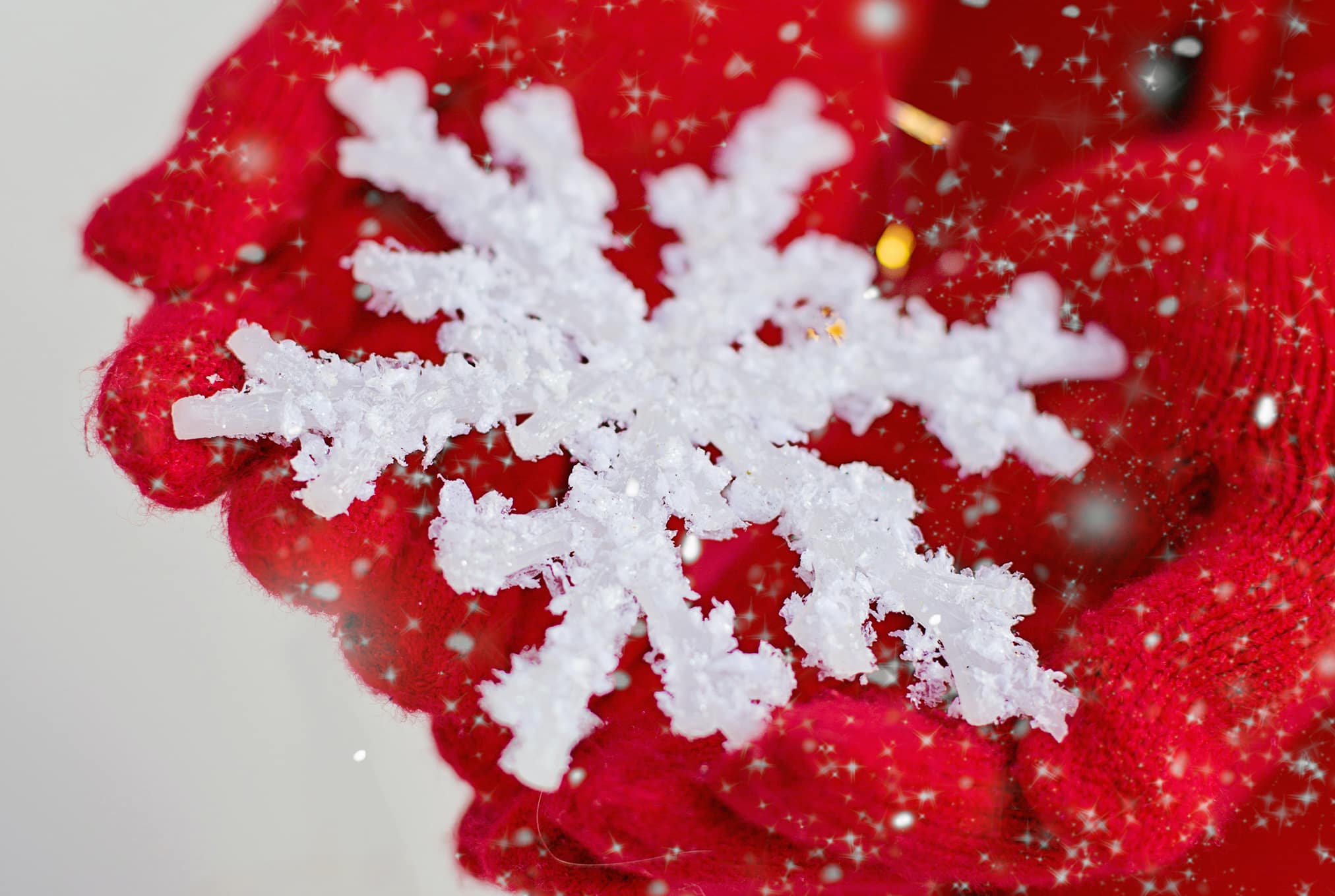 red gloves holding a sparkly white snowflake